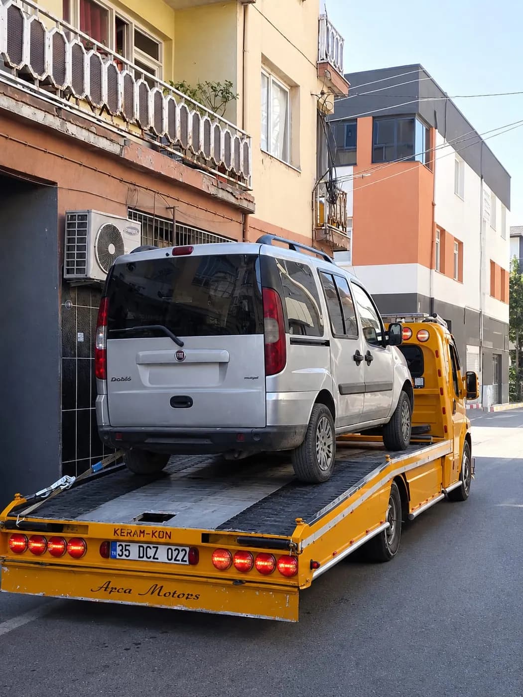 Sarı platform çekici üzerindeki beyaz minibüs
