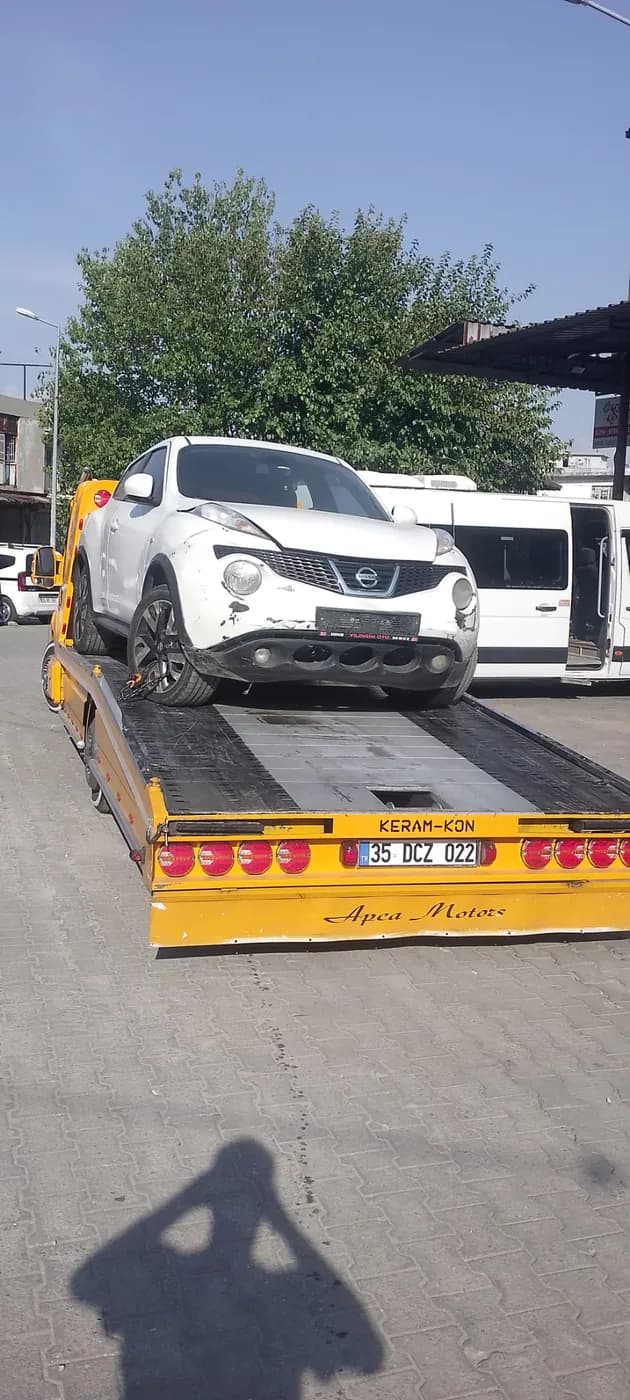 Sarı platform çekici üzerinde taşınan beyaz SUV