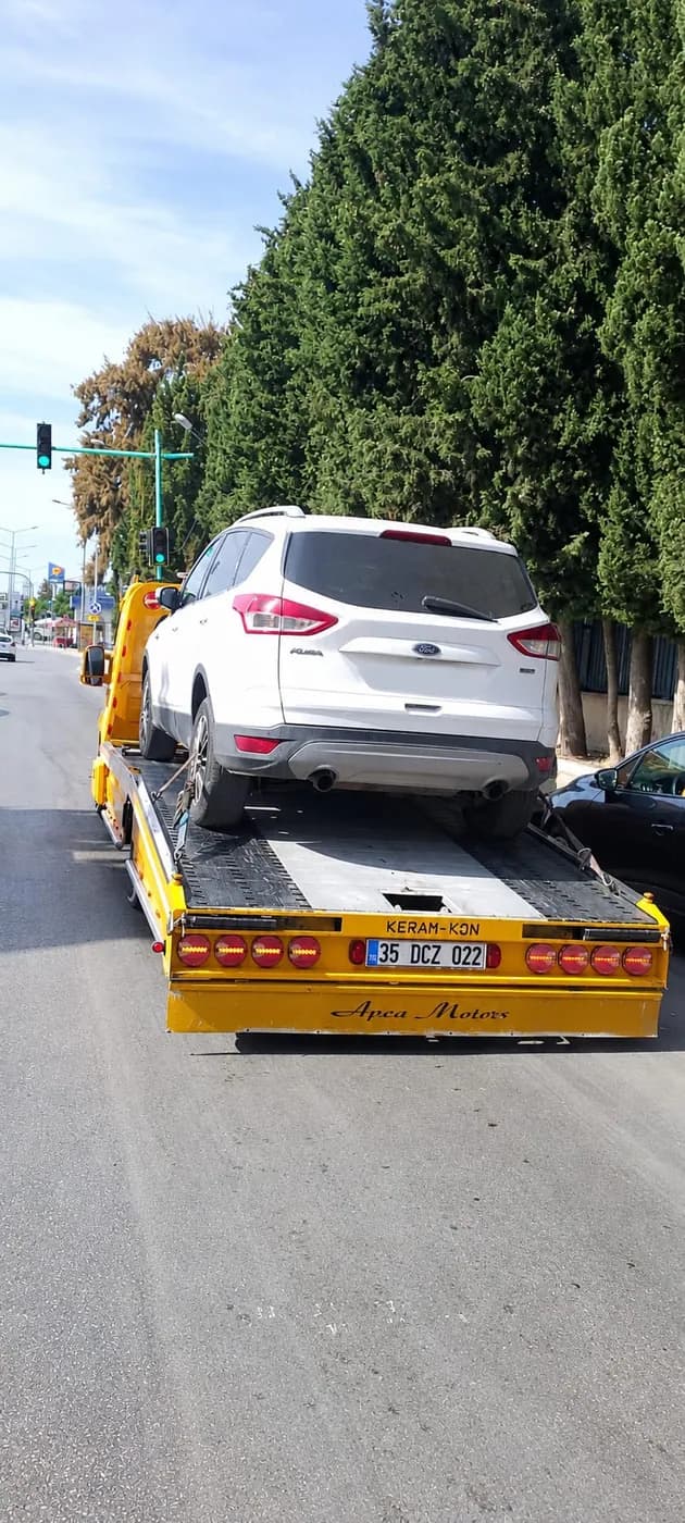 Yol kenarında sarı platform üzerindeki beyaz SUV