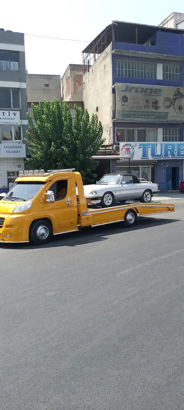 Cadde üzerinde sarı çekiciyle beyaz otomobil taşıma