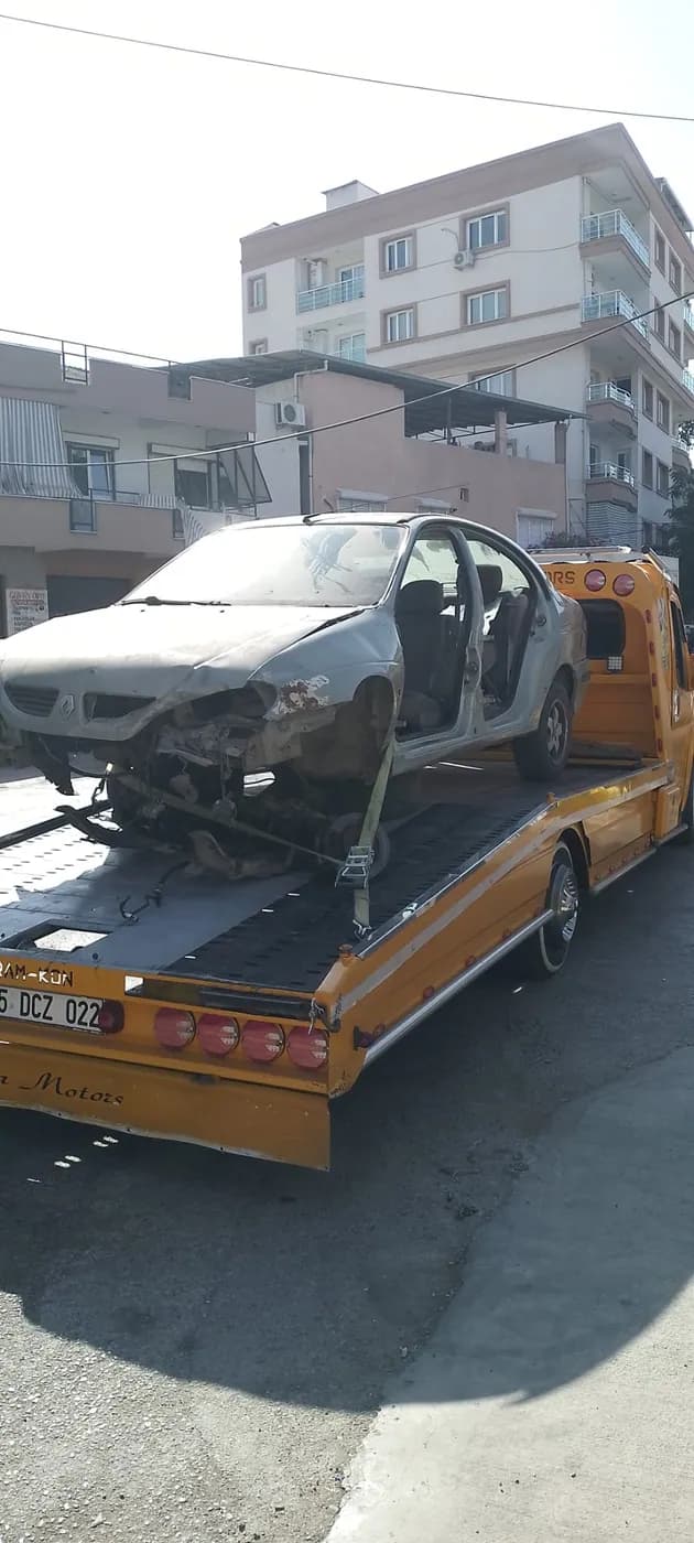 Ön bölümü hasarlı beyaz otomobilin platform çekici üzerinde taşınması