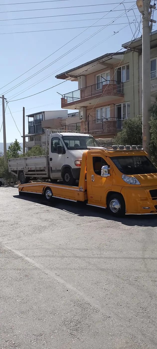 Cadde üzerinde sarı çekiciyle taşınan beyaz kamyonet