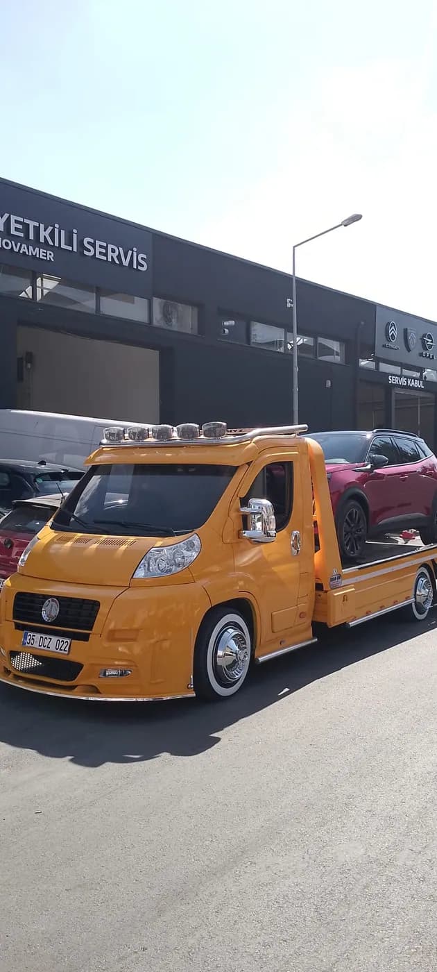 Servis önünde sarı çekici üzerindeki kırmızı otomobil