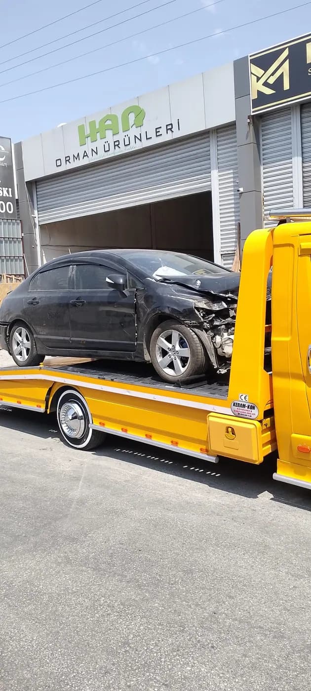 Servis girişinde sarı çekici üzerinde siyah otomobil